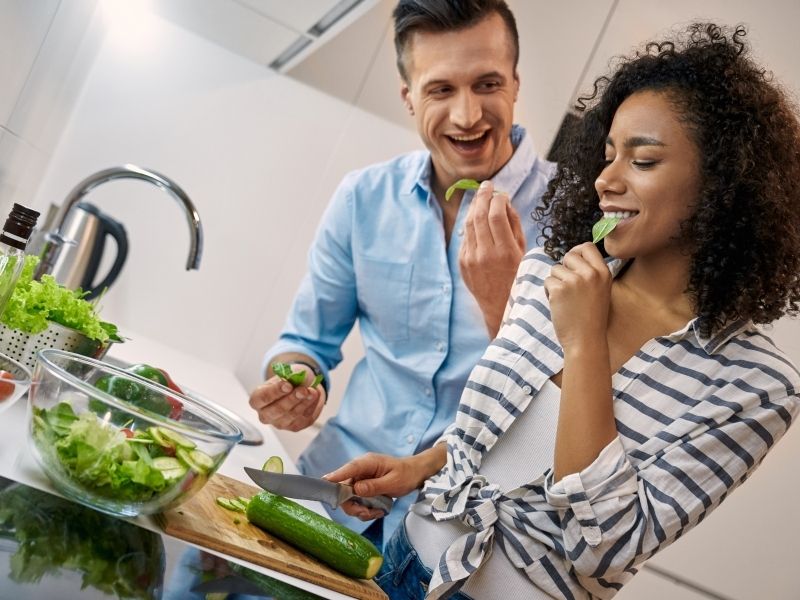 Couple playfully prep dinner together in a modern kitchen