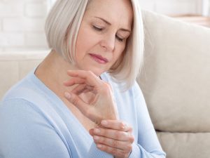 woman holding wrist to illustrate osteoporosis caused by lack of estrogen post hysterectomy