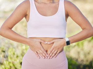woman with hands on stomach to illustrate healthy nutritional assessment