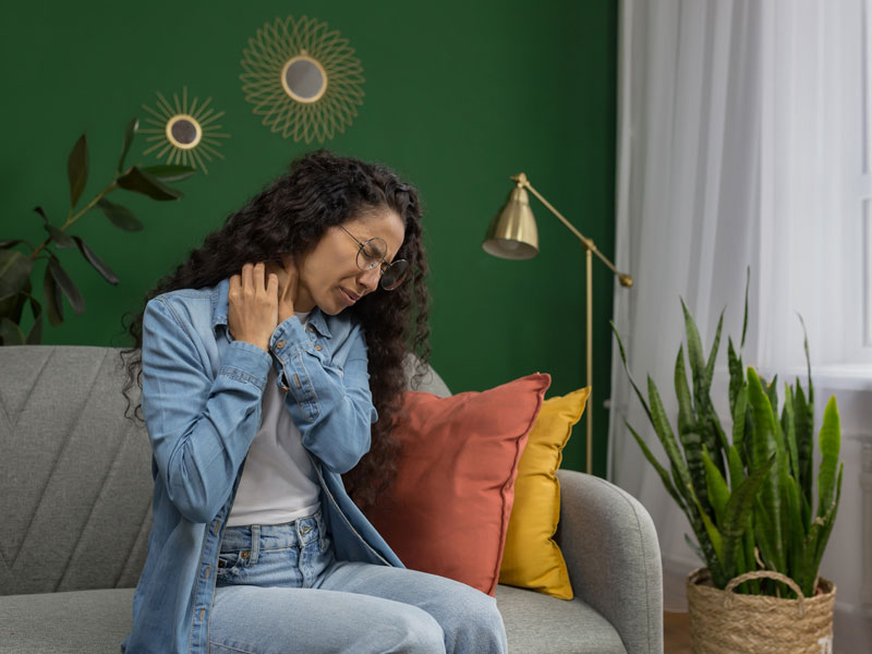 business woman at home holding neck in agony to illustrate suffering chronic pain