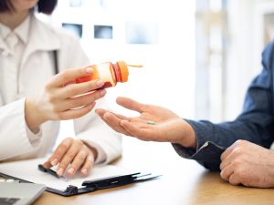doctor handing out pills for when medication is needed for chronic pain treatment