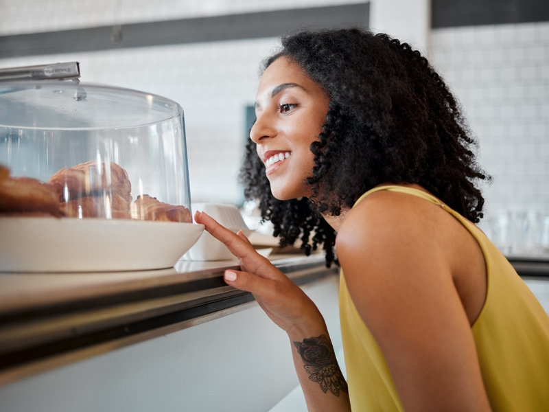 happy woman looking at croissants to illustrate food cravings