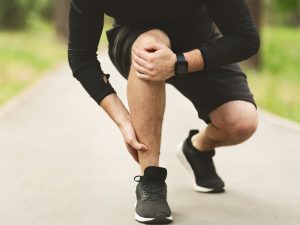 male runner stopping to feel an acute pain in his leg