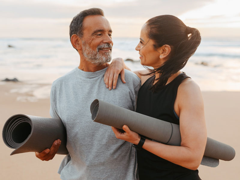 Two seniors enjoying healthy longevity on the beach exercising