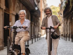 Older couple enjoying longevity riding though city on bikes