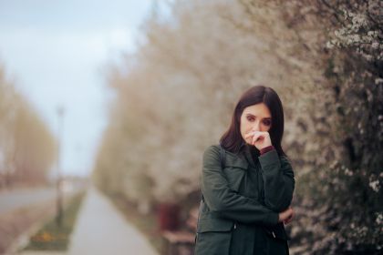 Woman stands outside on a cold day in the fall looking sad