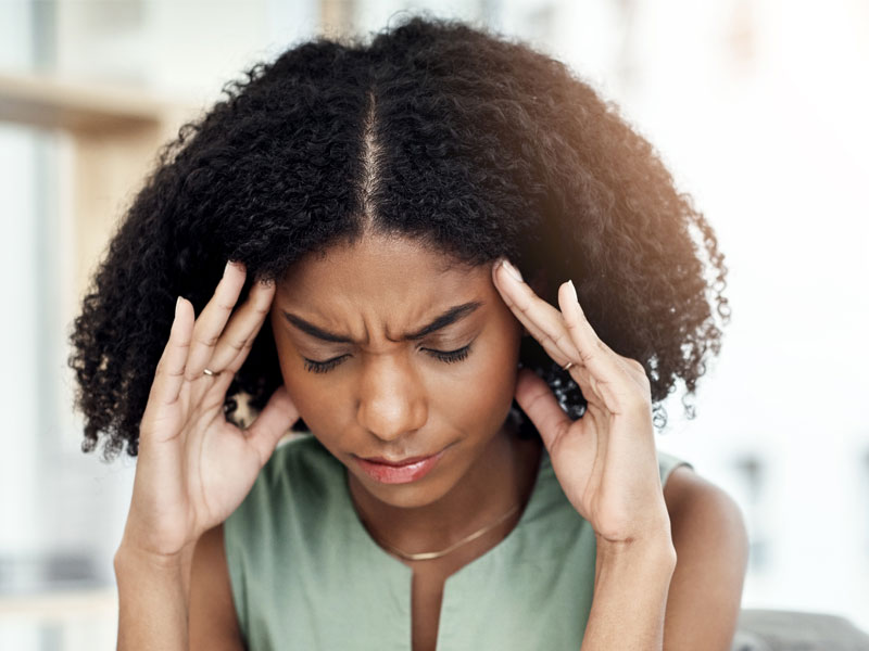 Woman suffering with headache to illustrate signs of low progesterone