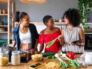 Three women enjoying preparing healthy food to illustrate the role of calcium and magnesium in the diet