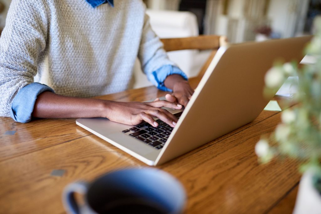 Closeup of an African American female entrepreneur working online with a laptop while sitting at her table at home