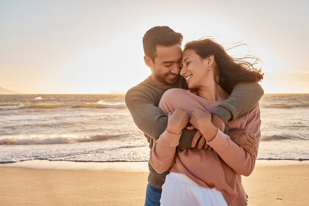Young diverse biracial couple having fun at the beach together. Young diverse biracial couple being romantic at the beach together.