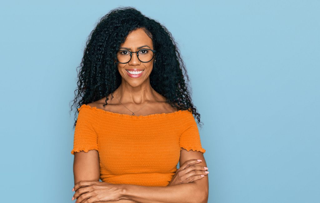 Middle age african american woman wearing casual clothes and glasses happy face smiling with crossed arms looking at the camera. positive person.